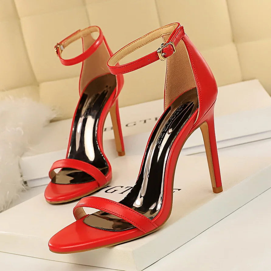 Red high-heeled sandals on a white surface with a beige background