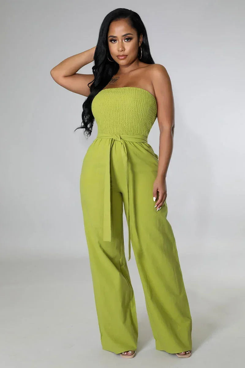 Woman wearing a green strapless jumpsuit on a plain background