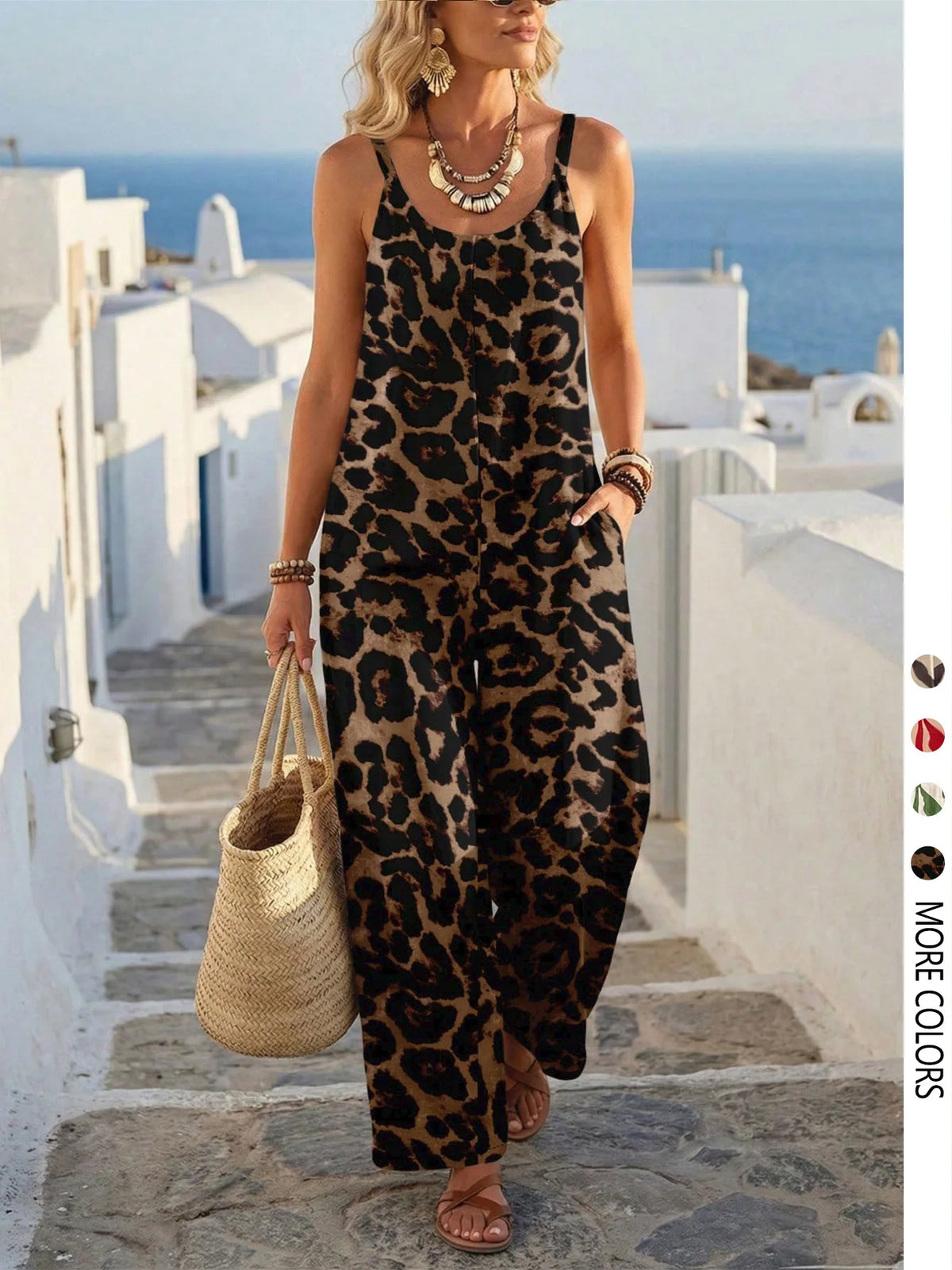 Woman in a leopard print dress standing on a Mediterranean-style street with white buildings and blue sky.