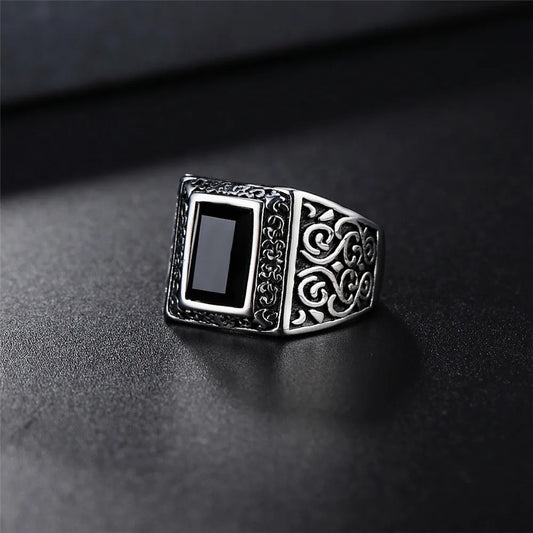 Silver ring with black stone on a dark surface