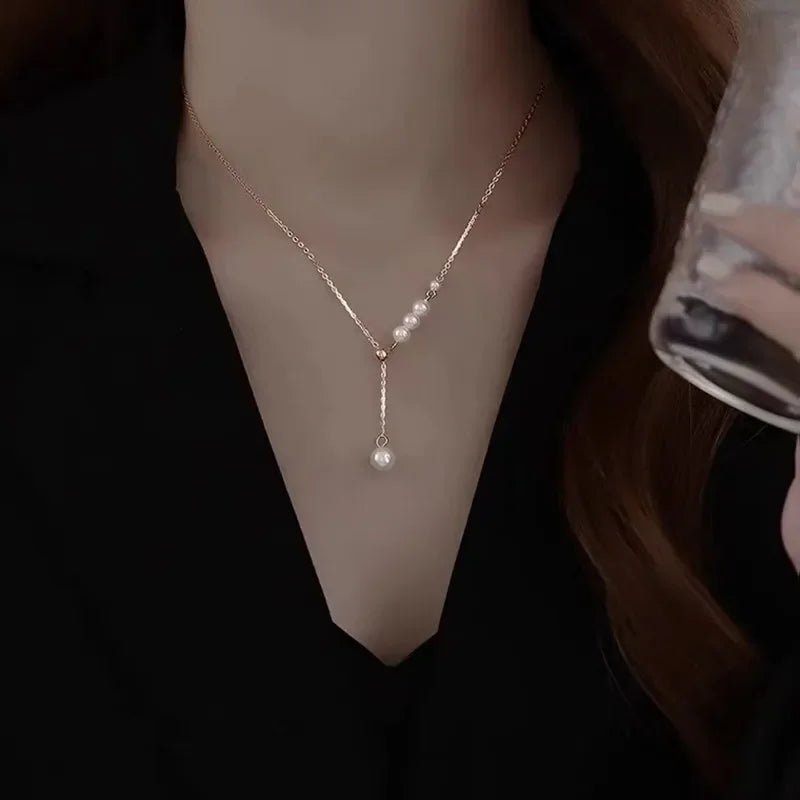 Pearl necklace being held by a hand against a dark background