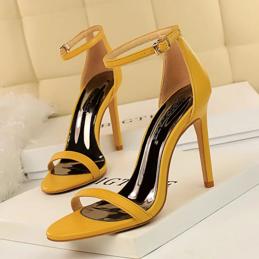 Yellow high-heeled sandals on a white surface with a blurred background