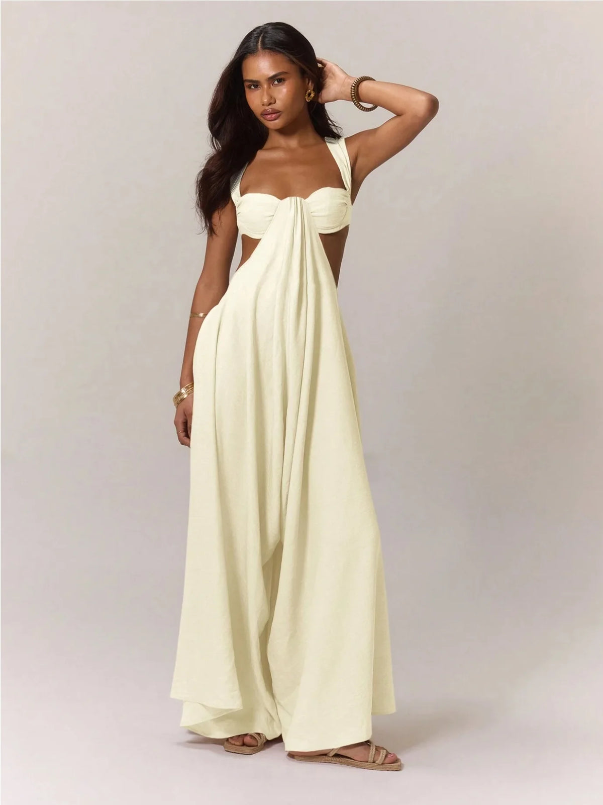 Woman wearing a strapless, long, light-colored dress against a plain background