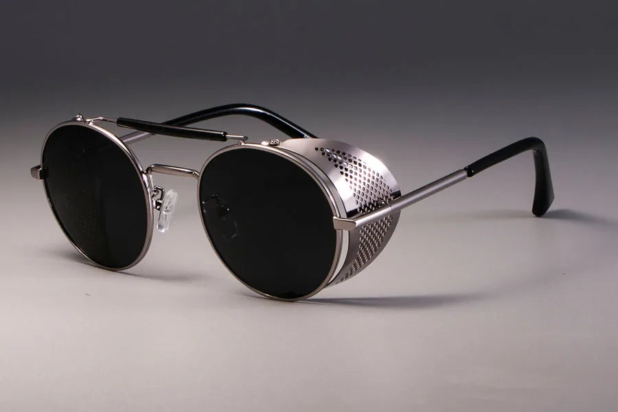 Steampunk-style sunglasses with metallic frame and black lenses on a gray background