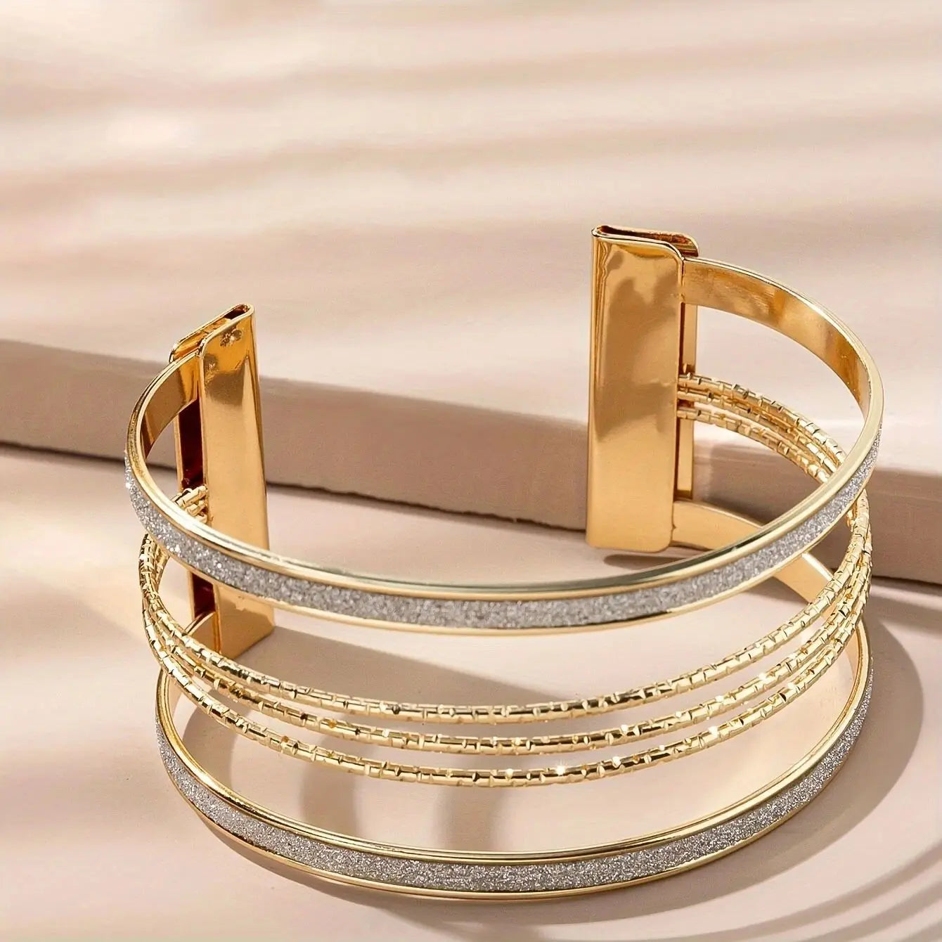 Gold bracelet with multiple layers on a beige background