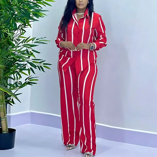 Woman wearing a red and white striped outfit standing next to a potted plant.
