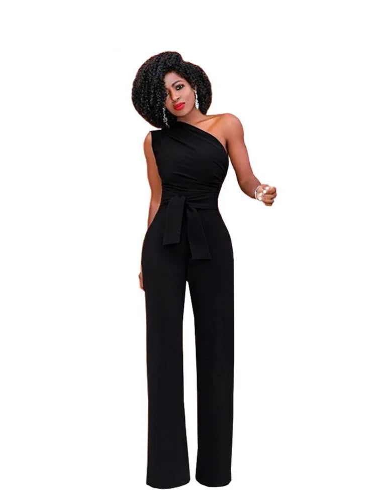 A woman modeling an elegant one-shoulder belted jumpsuit in black color with accessories.