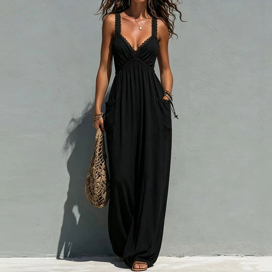 A woman models a black sleeveless Jumpsuit with lace-up spaghetti straps, a V-neckline, and side pockets, standing against a textured gray wall.