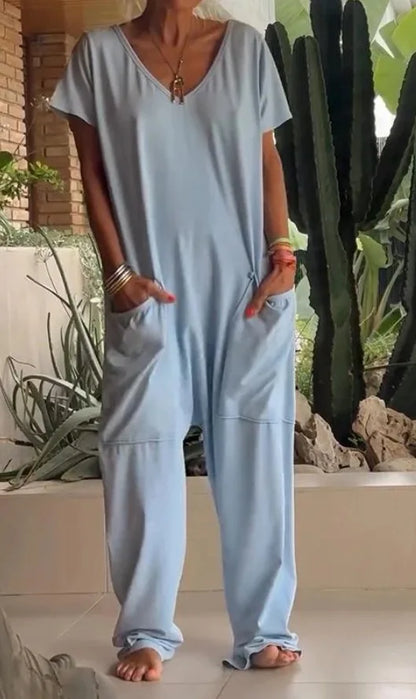 Person wearing a light blue jumpsuit standing in front of a cactus plant.