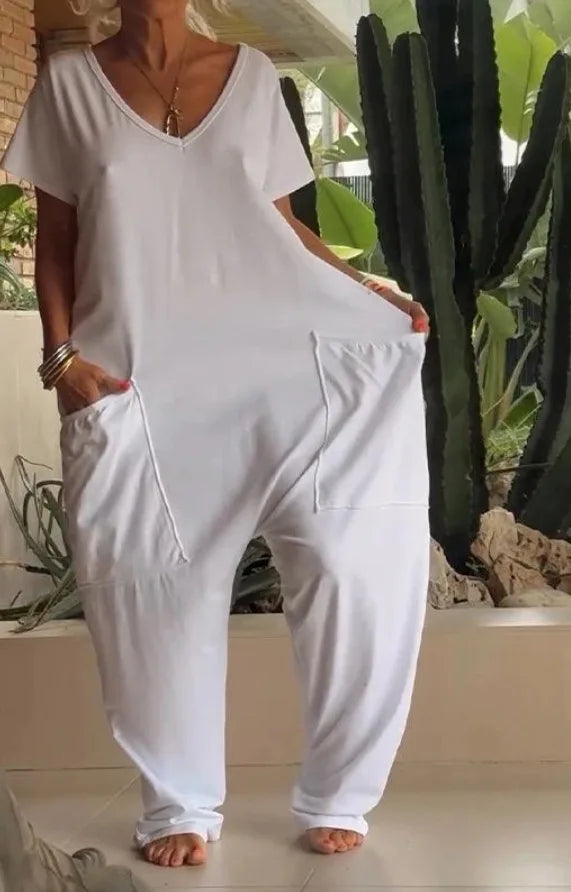 Person wearing a white jumpsuit standing in front of a cactus plant.