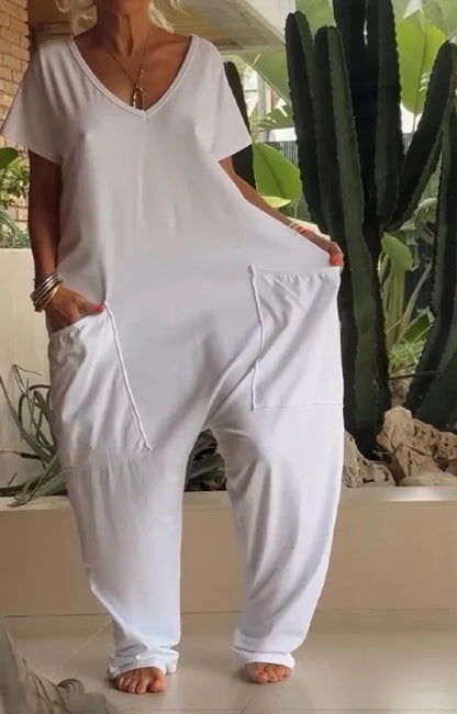 Person wearing a white jumpsuit standing in front of a cactus plant.