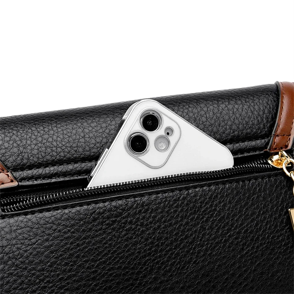 Black leather handbag with a gold zipper and a white phone inside