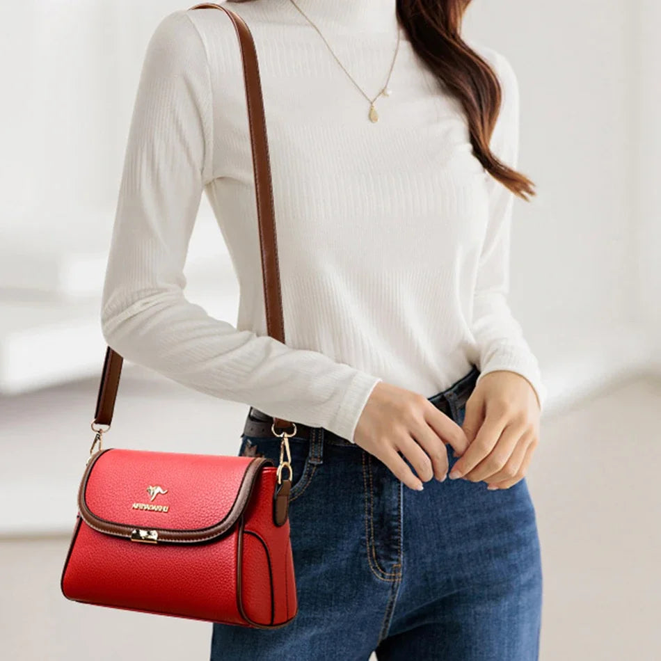 Person wearing a white sweater and blue jeans with a red handbag on a light background