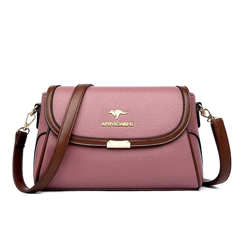 A dusty pink pebbled leather crossbody handbag with brown leather trim, a gold kangaroo logo, and the brand name 'AFEDADAERU' on the front flap, shown against a plain white background.