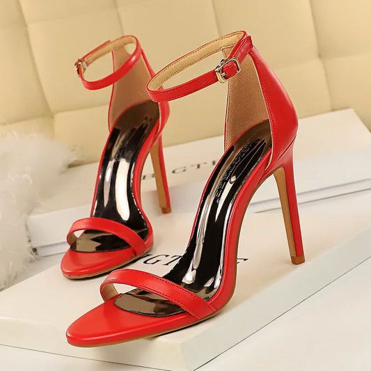 Red high-heeled sandals on a white surface with a beige background