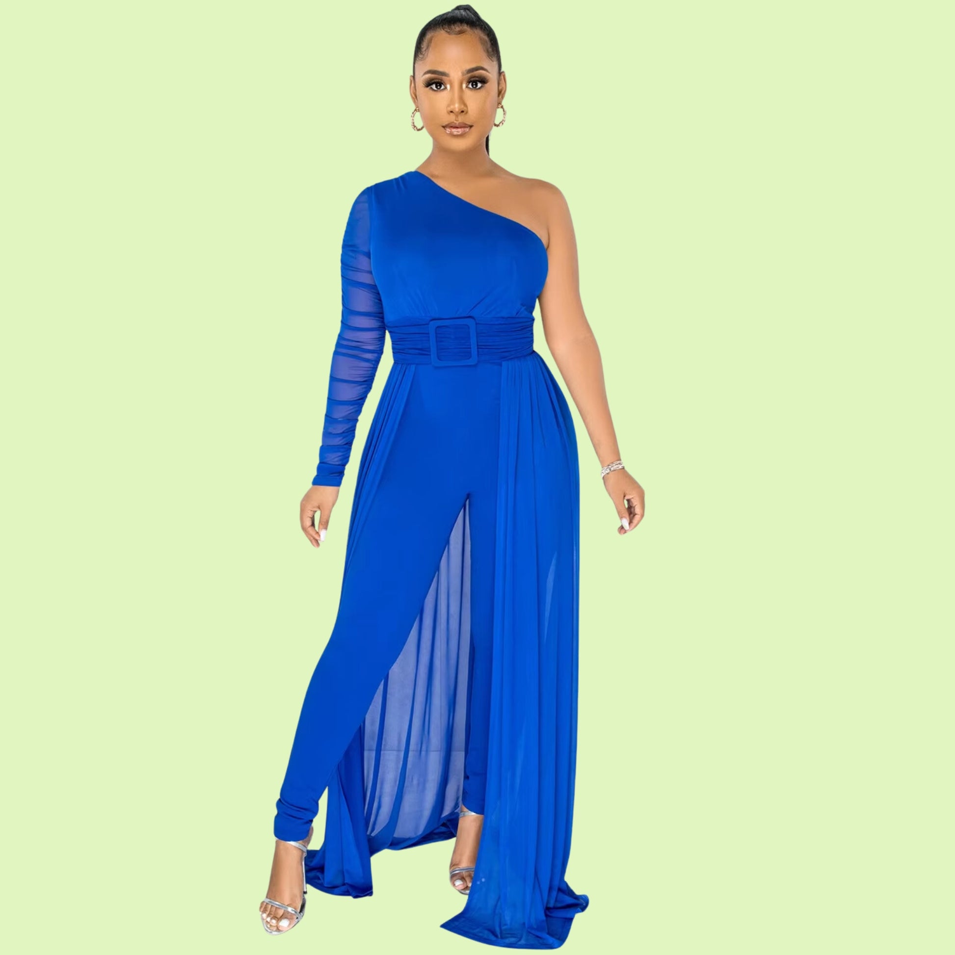 A stylish blue jumpsuit with a single-shoulder silhouette, a ruched sheer long sleeve, and a wide belt at the waist. The look is completed with a flowing sheer train and silver jewelry, set against a pastel green backdrop.