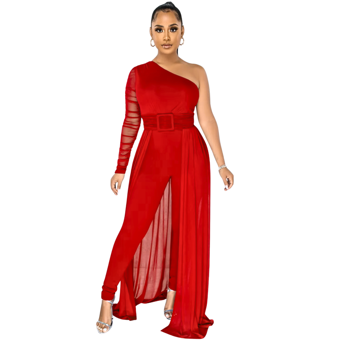 A woman wearing an elegant red one-shoulder jumpsuit featuring a sheer, long-sleeved arm, a belted waist, and a dramatic flowing overlay with a front slit. She accessorizes with silver hoop earrings, a bracelet, and metallic heels.