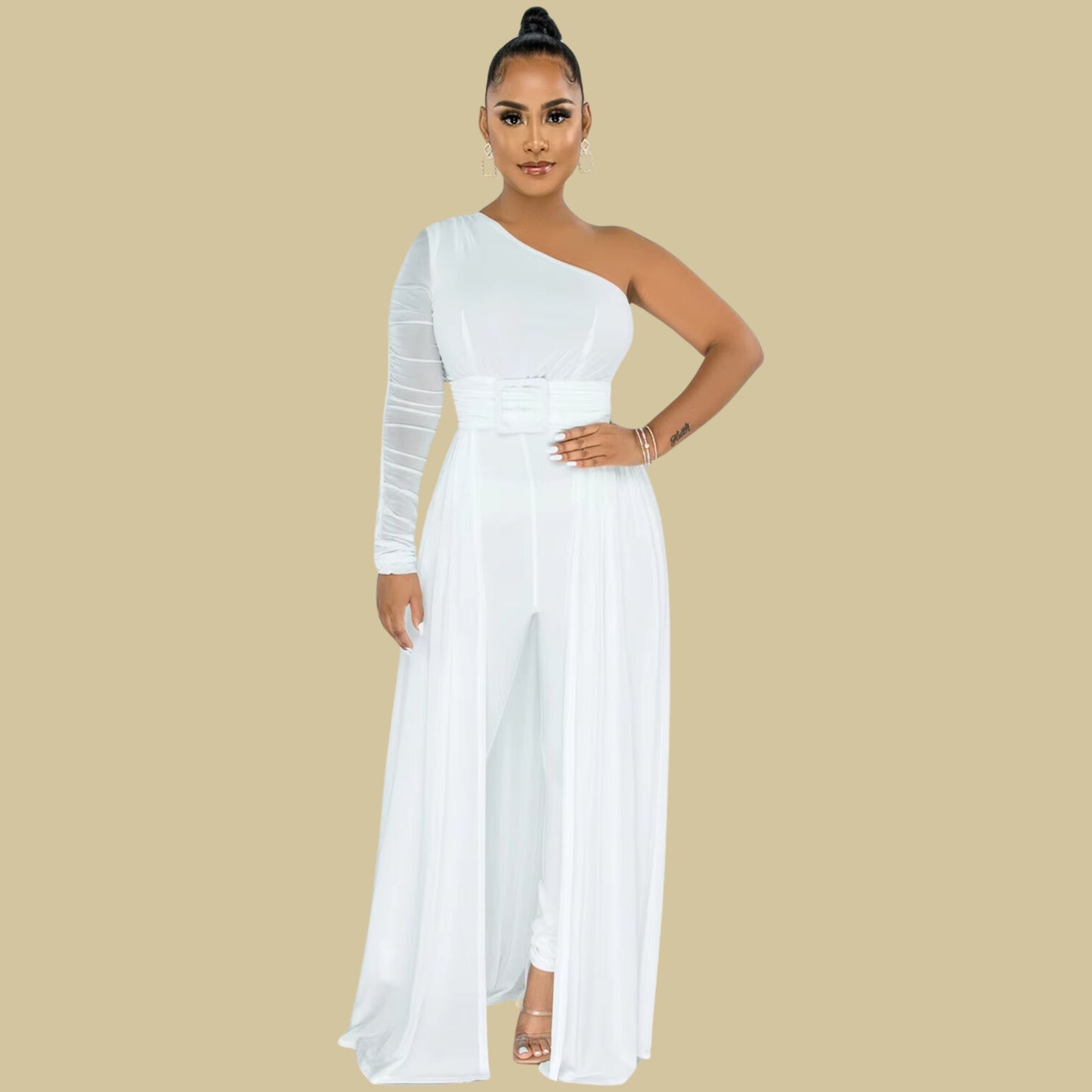 A formal white jumpsuit with a single-shoulder silhouette, a sheer ruched sleeve, and a flowing train with a slit. The outfit is accessorized with silver earrings, a bracelet, and open-toe metallic heels.