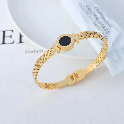Gold bracelet with a black stone on a light background