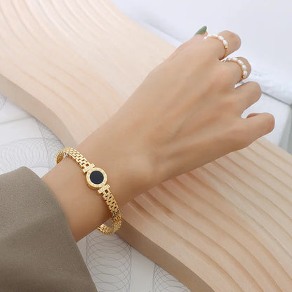 Gold bracelet with a black stone for a casual elegant look.background