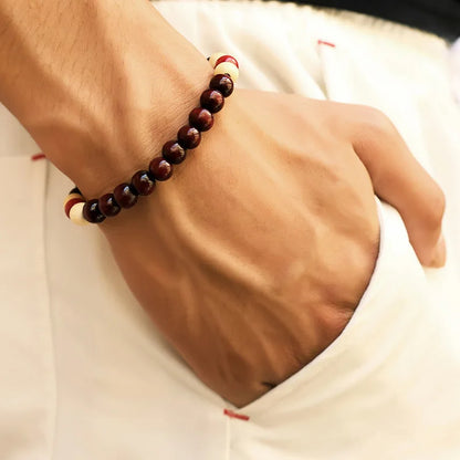 Close-up of a wrist wearing a red beaded bracelet on a white background