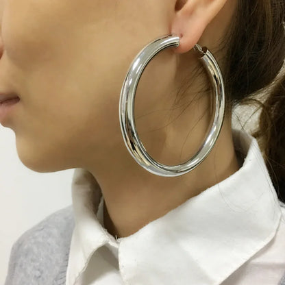 Close-up of a person wearing a large silver hoop earring.