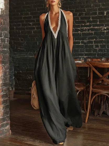 Woman wearing a long black dress with white lace details in a rustic setting.