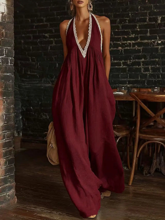 Woman wearing a burgundy dress with lace trim in a dimly lit room.