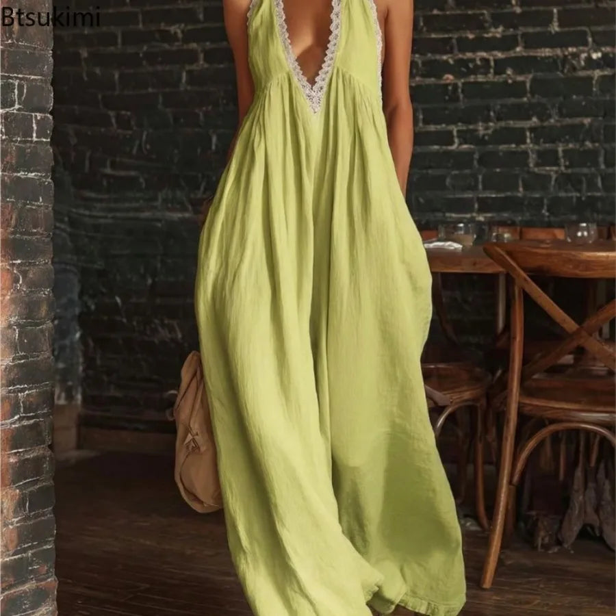 A woman wearing a flowing light yellow-green maxi dress with a deep V-neck trimmed in white lace, standing in a rustic indoor setting with a dark brick wall and wooden furniture.