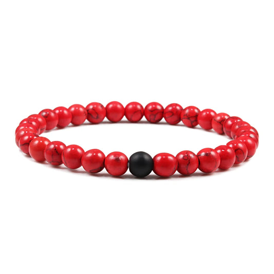 Red beaded bracelet with a black bead on a white background