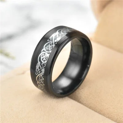 Black ring with white engraved design on a beige surface