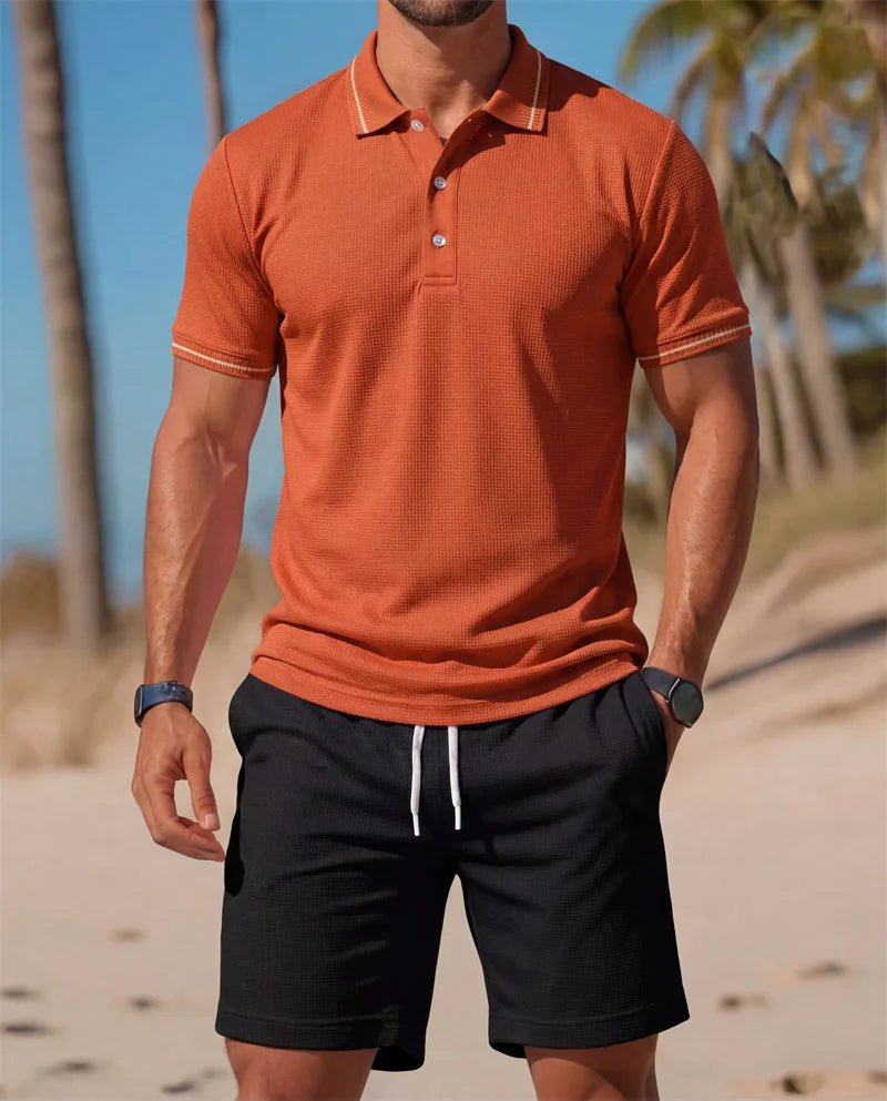 Man wearing an orange polo shirt and black shorts on a beach with palm trees in the background