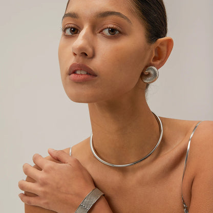 Woman wearing a silver necklace and earrings against a neutral background
