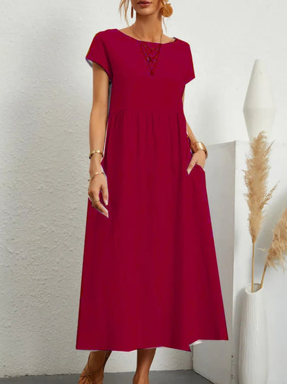 Red dress worn by a person against a white wall with decorative elements.