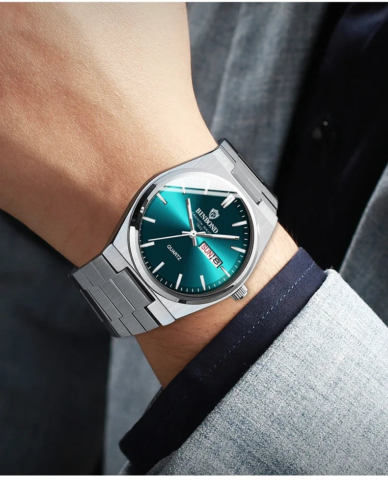 Silver watch with a blue face on a person's wrist, wearing a gray suit.