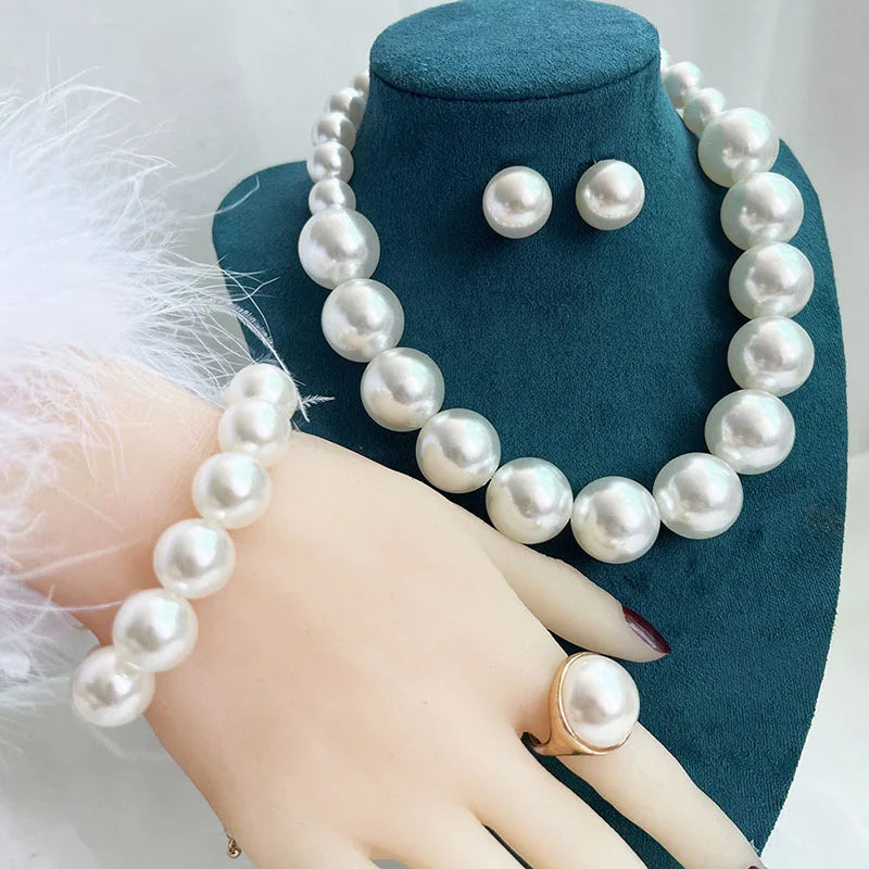 Pearl necklace, earrings, and ring set on a mannequin hand with a teal stand.