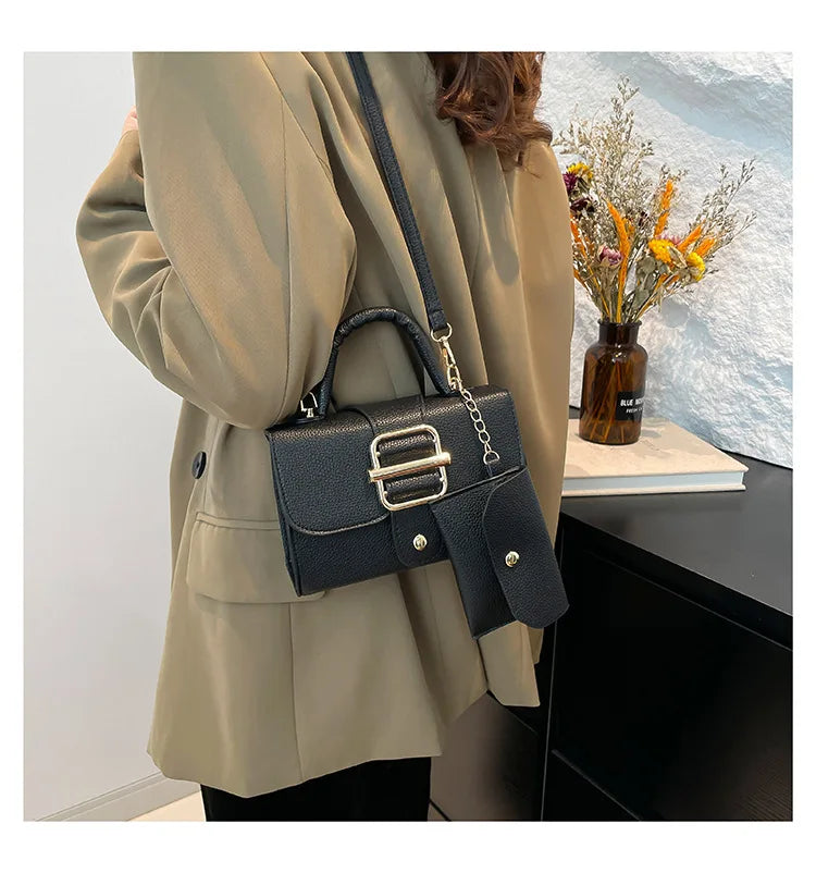 Person wearing a beige coat with a black handbag, standing indoors.