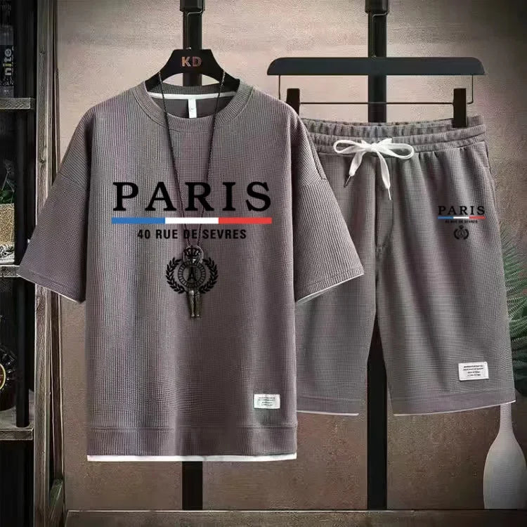 Gray 'Paris' t-shirt and shorts set on hangers against a neutral background