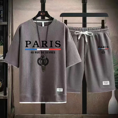 Gray 'Paris' t-shirt and shorts set on hangers against a neutral background