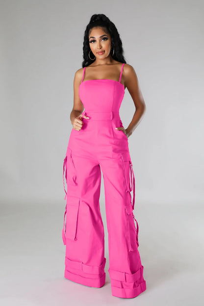 Woman wearing a bright pink jumpsuit on a plain background