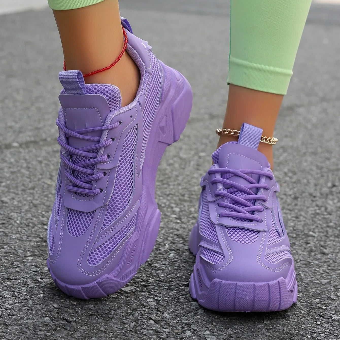Purple sneakers worn on a gray pavement surface
