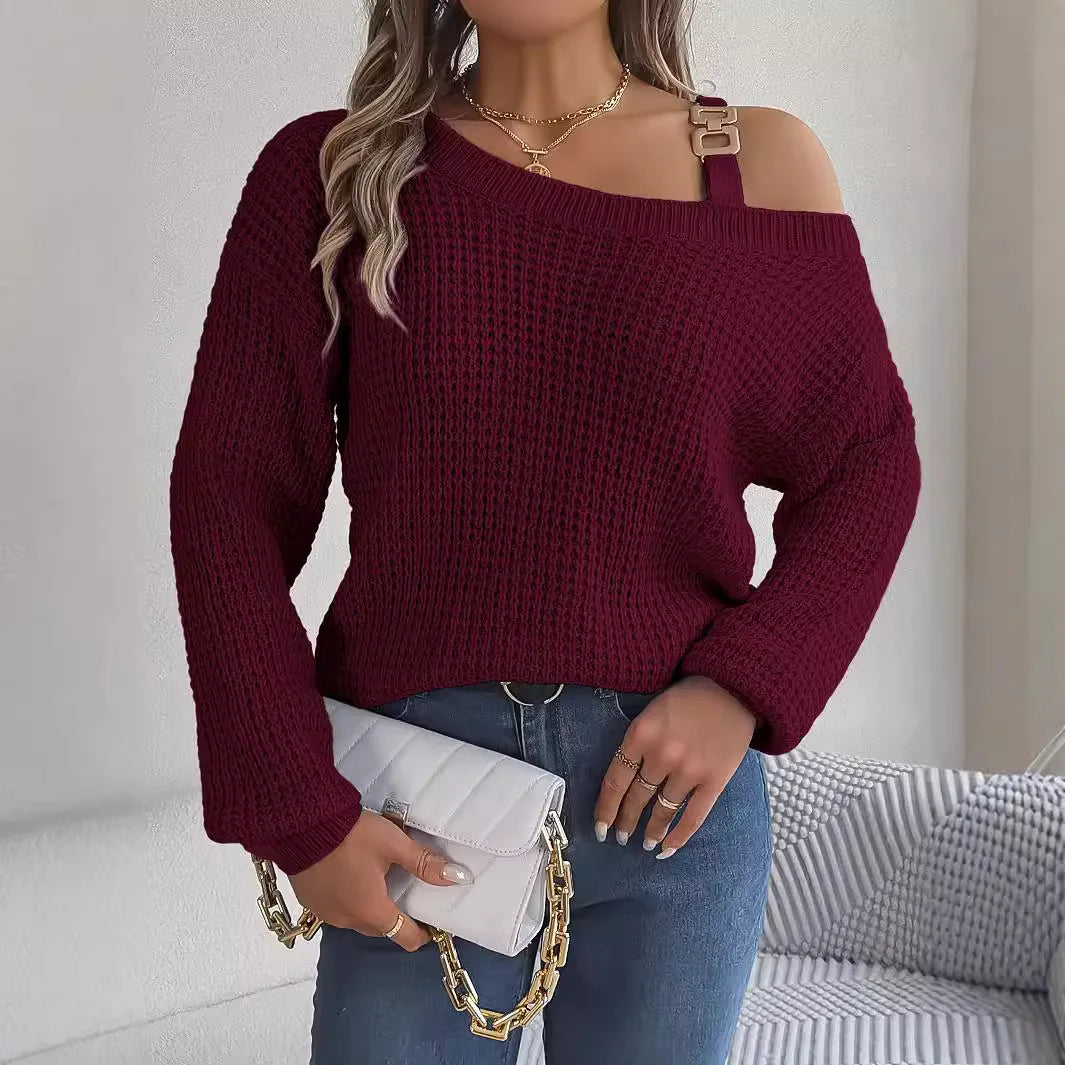 Woman wearing a burgundy sweater with a cold shoulder design, holding a white clutch.