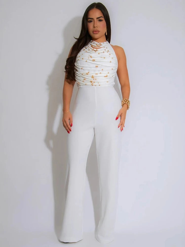 Woman wearing a white outfit with gold embellishments on a plain background