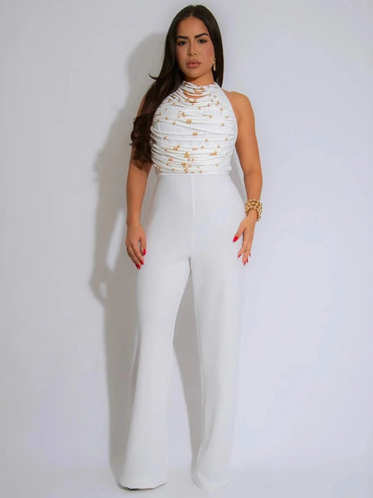 Woman wearing a white outfit with gold embellishments on a plain background