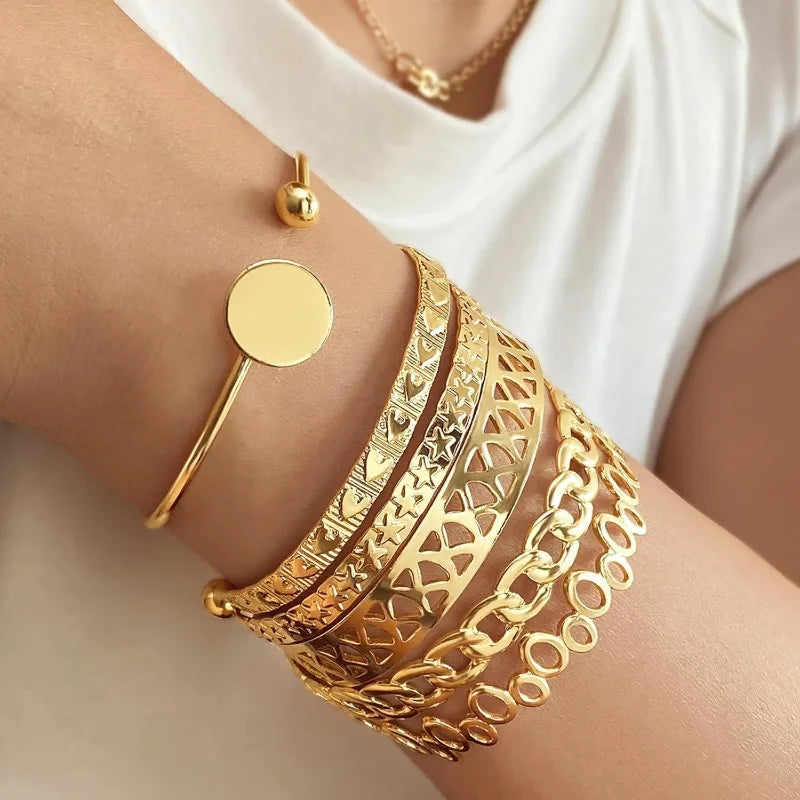 Gold bracelets on a person's wrist with a white background