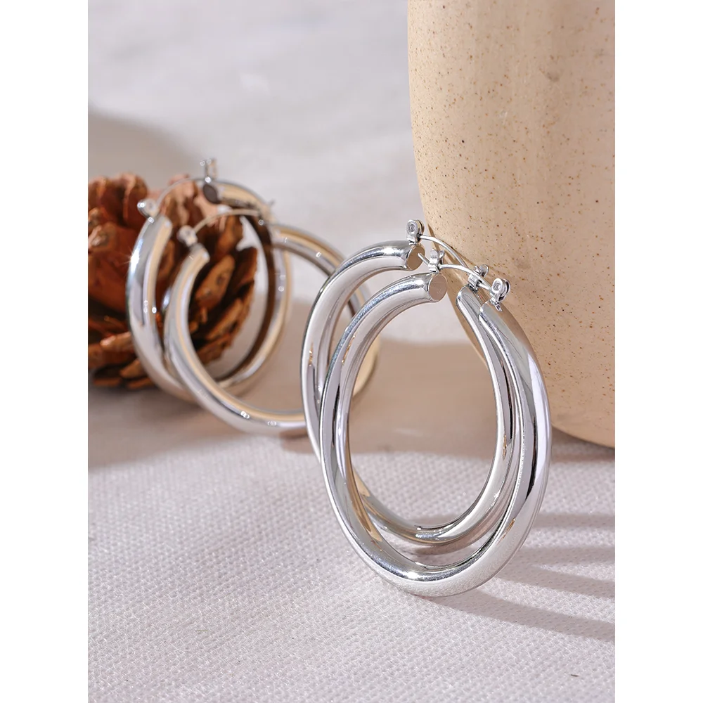 Silver hoop earrings on a textured surface with a neutral background
