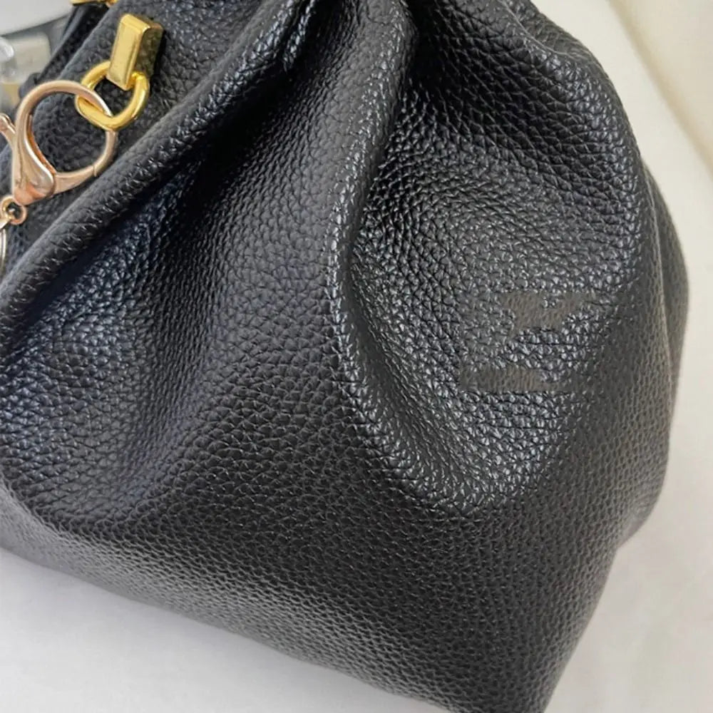 Close-up of a black textured handbag with a gold clasp on a light background
