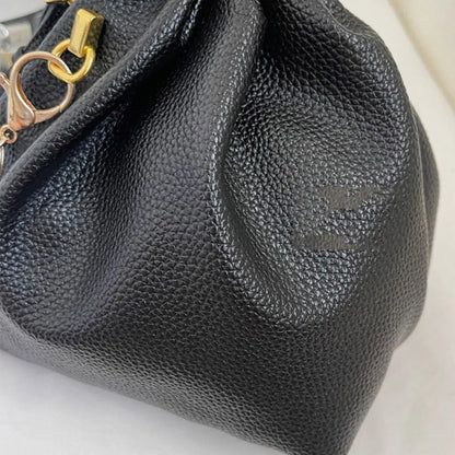Close-up of a black textured handbag with a gold clasp on a light background