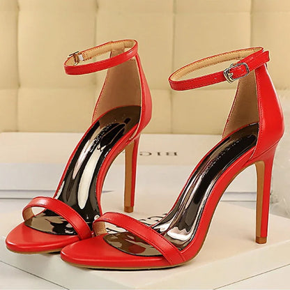 Red high-heeled sandals with thin straps on a light background