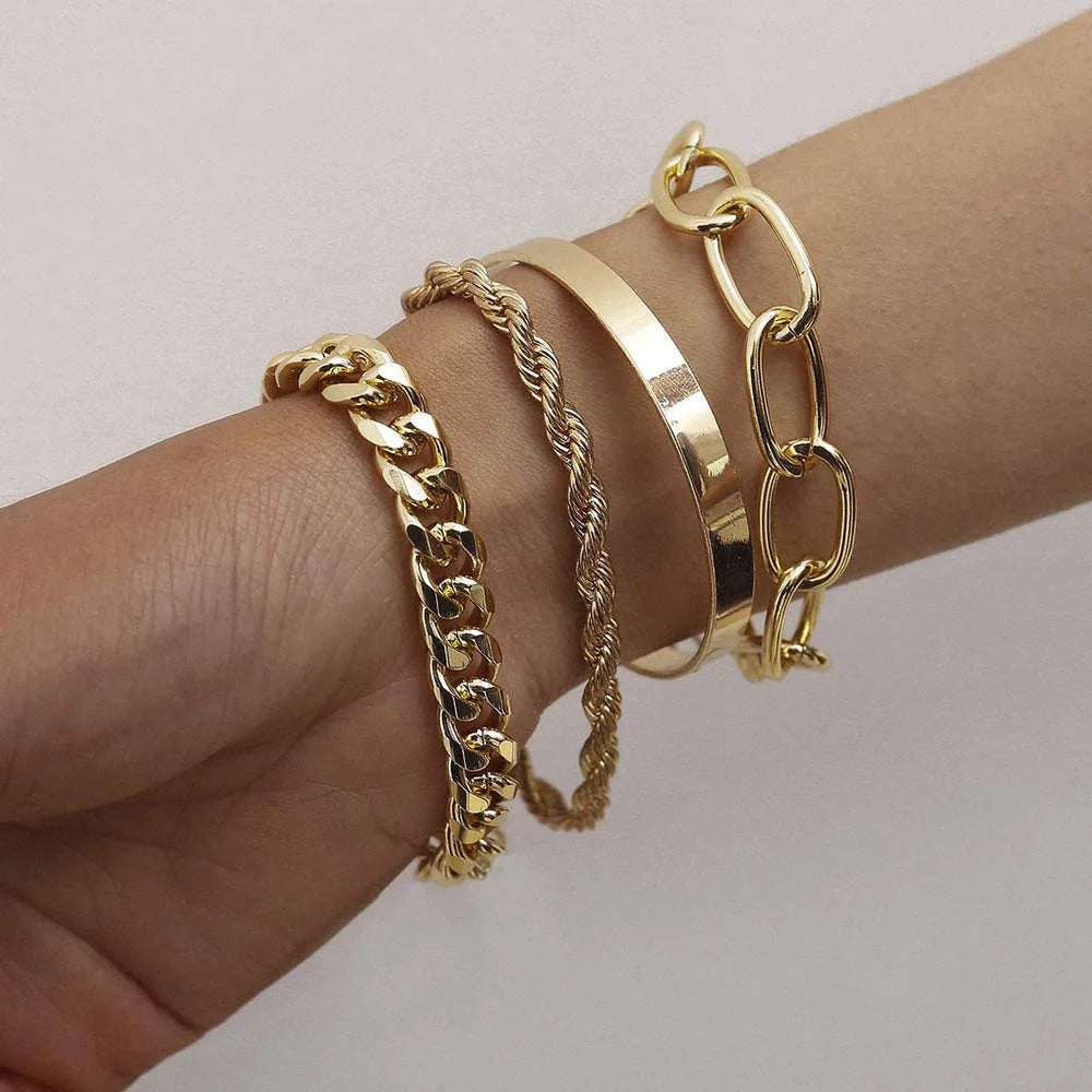 Gold bracelets on a wrist against a light background